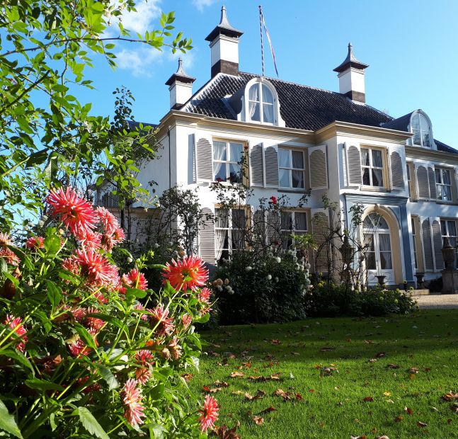 De voorgevel van Nieuwerhoek met bloeiende dahlia's ervoor